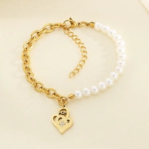 Detail of heart pendant with MOM engraving on gold chain and white pearl bracelet