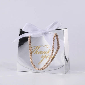 Detail of silver mirror gift bag with golden Thank You text and white ribbon bow