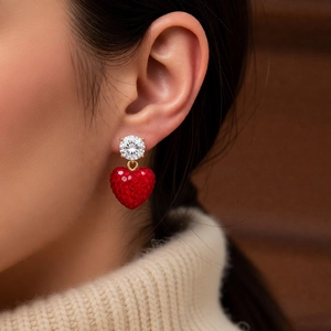 Gros plan de boucles d'oreilles cœur avec pendentif rouge et zircone portées par un mannequin