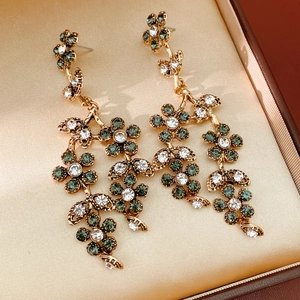 Close-up of vintage golden flower drop earrings with green and clear rhinestones