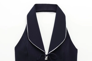 Detail of navy blue halter neckline featuring intricate white lace trim and woven texture