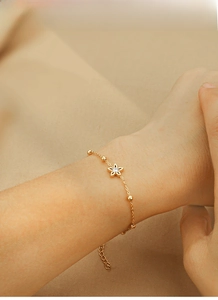 Macro shot of gold plated titanium steel flower charm bracelet with sparkling zircon stones