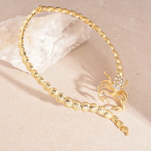 Gros plan d'un bracelet scorpion doré serti de strass sur un support en pierre