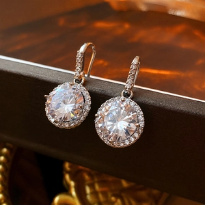 Close-up of silver hoop earrings with clear cubic zirconia pavé on textured background