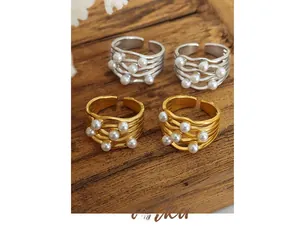Detail of vintage layered wave rings with pearls in gold and silver finish on wood
