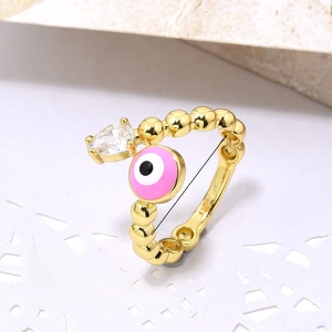 Detail view of gold evil eye ring with pink enamel, clear zircon and beaded texture band