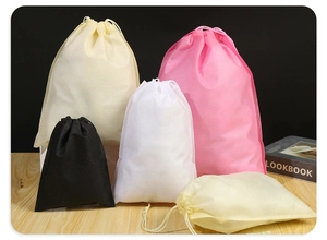 Detail of colorful non-woven drawstring storage bags in various sizes on wooden table