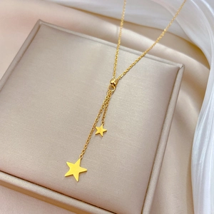 Detail view of gold tassel star Y-necklace on soft cushion with silk background