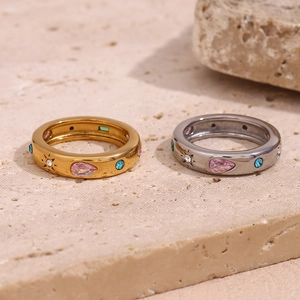 Close-up of gold and silver steel rings set with colorful teardrop and round gemstones
