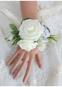 Detailed view of white artificial rose wrist corsage with ribbons for bridal wedding decor