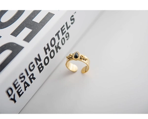 Detailed view of hammered 18K gold ring with a teardrop-shaped dark gemstone