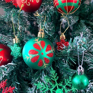 Primo piano di palline di Natale rosse e verdi con ciondoli a fiocco di neve su un albero