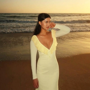 Detailed close-up of ruffle trim and deep V-neckline on a slim fit pale yellow dress