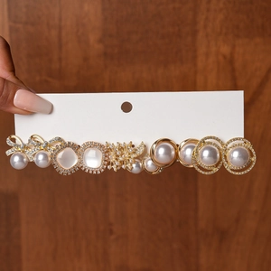 Detailed view of a 12-piece gold hair clip set with white pearls and sparkling rhinestones