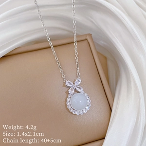 Detail view of silver bow necklace with white gemstone on elegant satin background