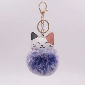 Close-up of cute cat pendant featuring a purple pompom and gold-tone metal key ring