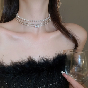 Detail of multi-layer pearl choker with rhinestones on a model in black feather dress