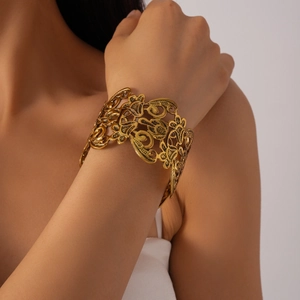 Detailed view of wide hollow floral pattern bracelet in vintage gold finish for women