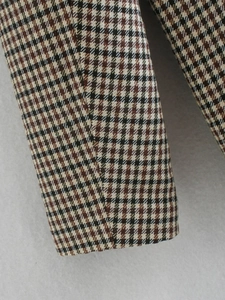 Macro detail of houndstooth wool fabric texture and fine stitching on plaid blazer sleeve