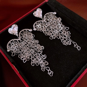 Detail of silver tassel earrings with heart-shaped rhinestones in a luxury jewelry box