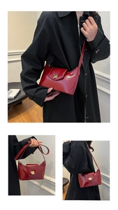 Close-up of red patent leather shoulder bag with gold metal buckle and glossy finish