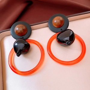 Detail of vintage round earrings with black resin disk and large orange acrylic ring