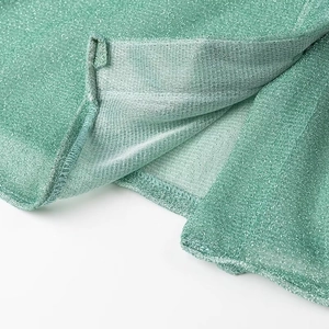 Gros plan détaillé sur la texture tricotée verte scintillante et l'ourlet de l'ensemble