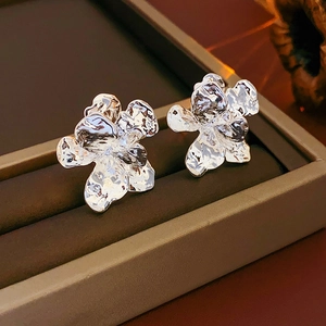 Macro detail of silver flower earrings with vintage crinkled metal texture in a box