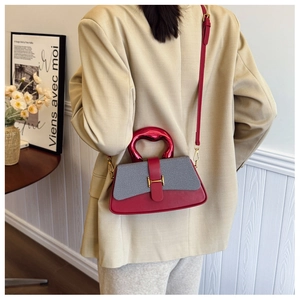 Detail of a red and grey contrast box bag with unique red metal handle and fine shoulder strap