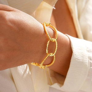 Detail of 18K gold plated cuff bracelet with braided texture on female wrist