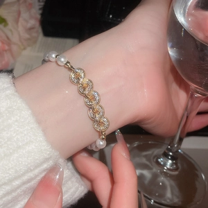 Detail view of pearl and gold chain bracelet with cubic zirconia on a female wrist