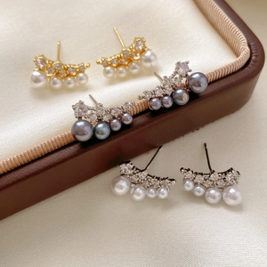 Macro shot of 18k gold and silver earrings with zircon accents and curved pearl rows