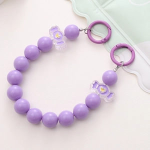 Detail of lavender purple beaded strap with candy charms and heart pattern on white surface