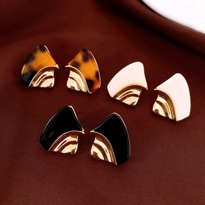 Vue détaillée de boucles d'oreilles géométriques en résine avec placage en métal doré texturé