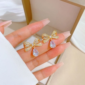 Detailansicht der goldenen Schmetterlings-Ohrringe mit lila Kristallen in der Hand
