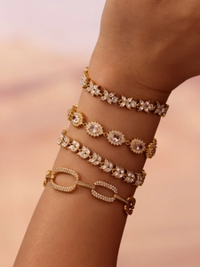 Detail of four gold clover and oval bracelets with cubic zirconia on a model's wrist