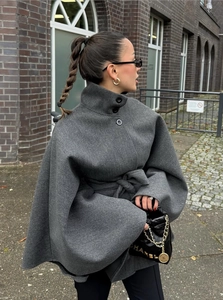 Détail d'un manteau cape en laine gris foncé avec col montant et manches chauve-souris