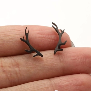 Close-up of matte black stainless steel reindeer antler stud earrings held by hand