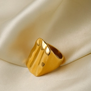 Macro d'une bague en acier inoxydable doré 18k avec texture ondulée sur de la soie
