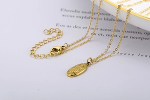 Gros plan du collier médaillon doré vintage avec gravure religieuse sur plateau blanc