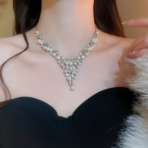 Gros plan du collier argenté en V avec perles élégantes et strass brillants sur le cou