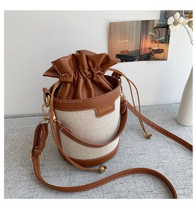 Detail of drawstring bucket bag made of brown leather and beige woven canvas