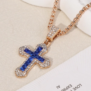 Macro shot of gold cross pendant featuring a deep blue center stone and pavé-set crystals