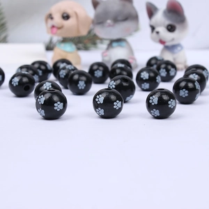 Detailed close-up of round black wooden beads featuring white paw print patterns