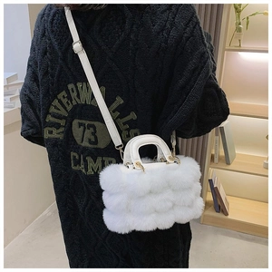 Close-up of a white plush faux fur handbag featuring gold-tone metal hardware and leather strap