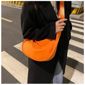 Detail of a bright orange crossbody dumpling bag in lightweight oxford nylon fabric