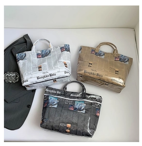 Flat lay view of newspaper print tote bags in white, brown, and black waterproof material