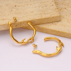 Gros plan de boucles d'oreilles créoles dorées style fondu sur socle en pierre