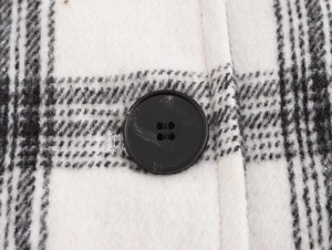 Detail of classic black and white plaid wool fabric and a black round button on a jacket