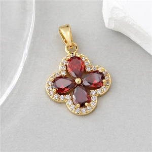 Macro detail of golden four-leaf clover pendant with red stones and white zirconia